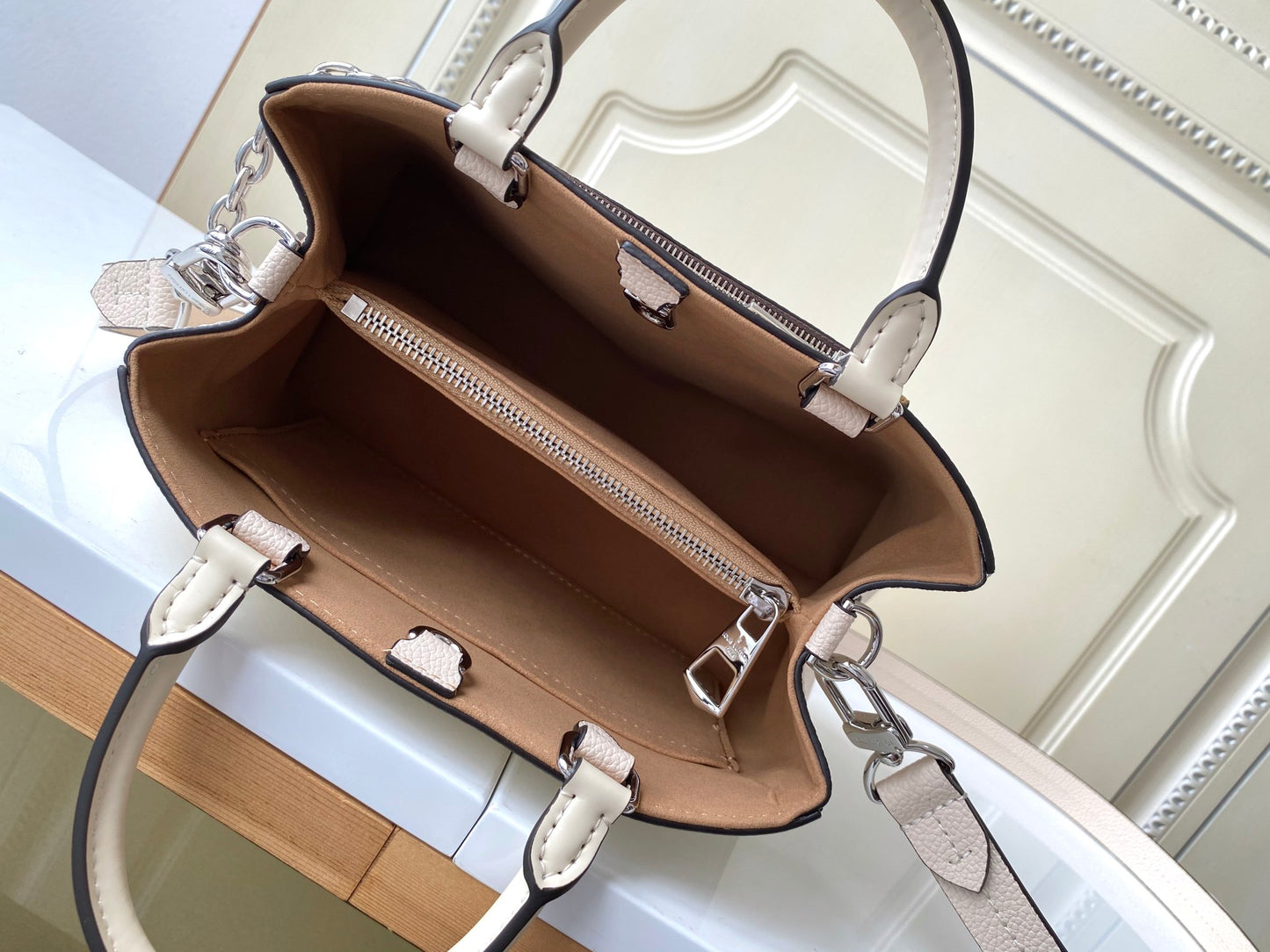 Louis Vuitton Elegant Cream Leather Handbag with Front Pocket and Chain Detail