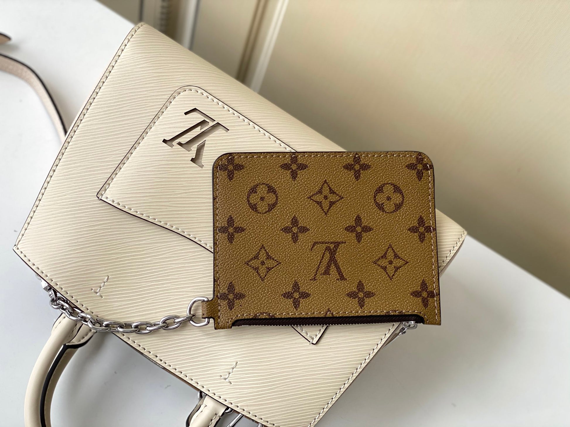 Louis Vuitton Elegant Cream Leather Handbag with Front Pocket and Chain Detail
