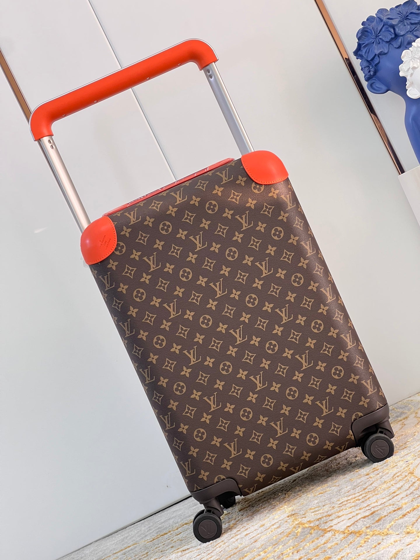 Brown Monogram Spinner Suitcase with Vibrant Orange Accents